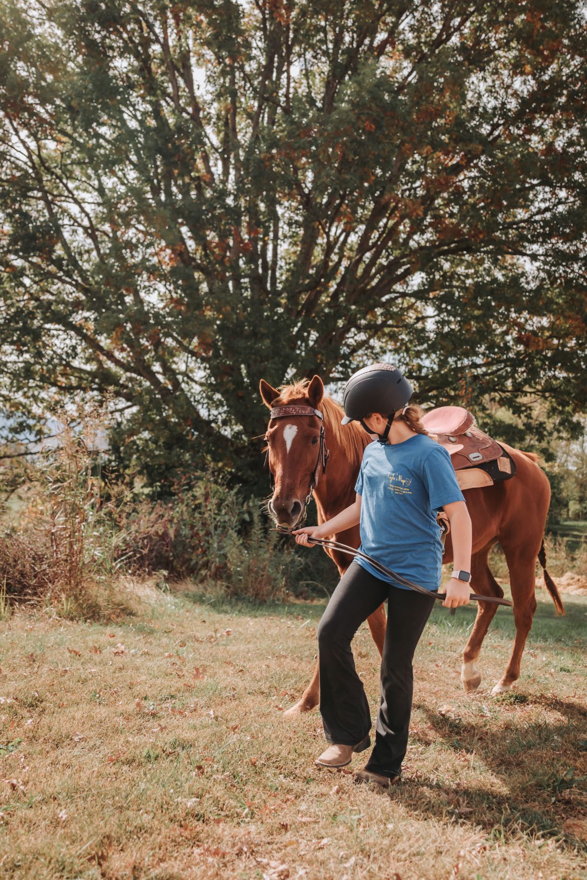 A young rider leading a horse in from the field